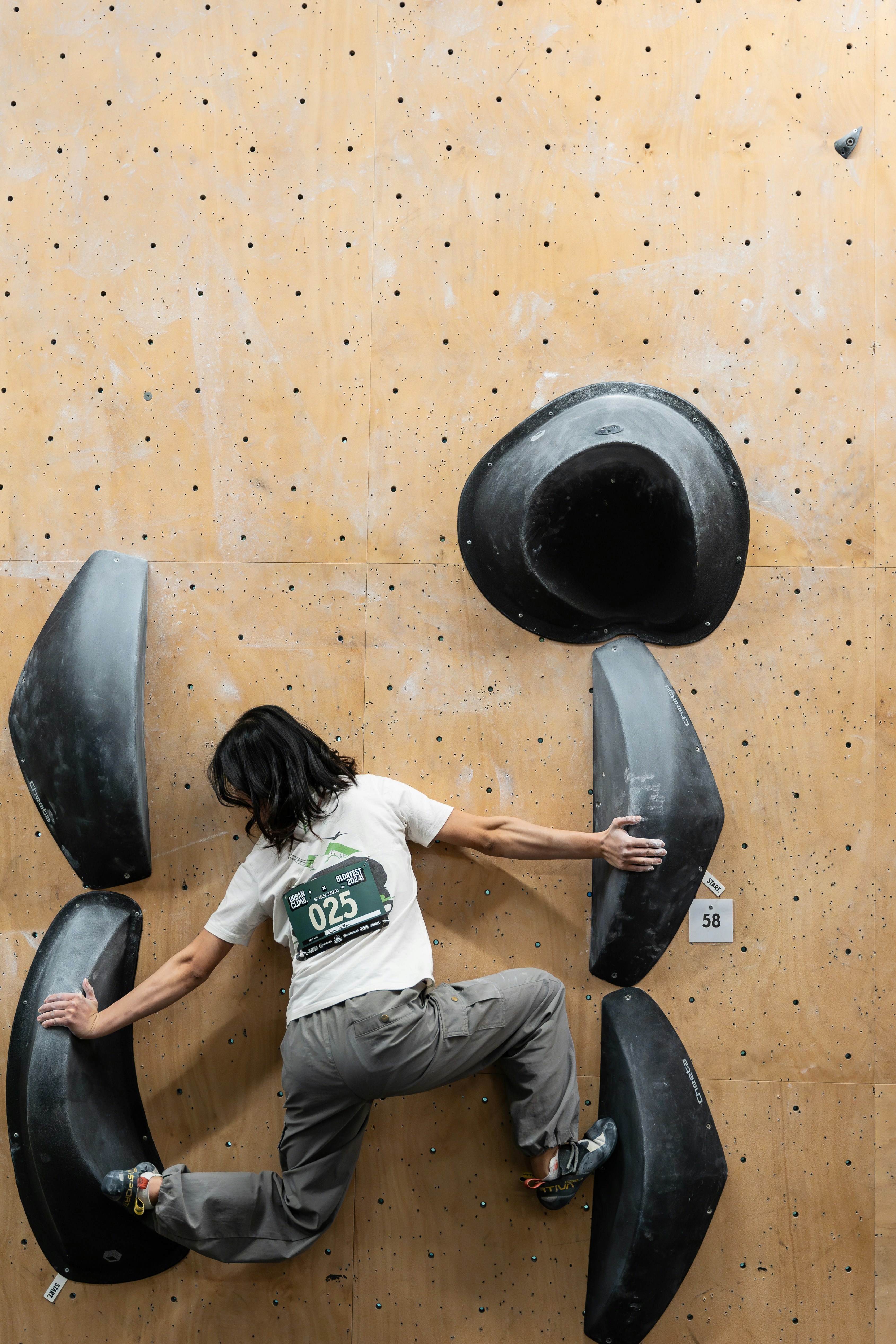 Climber practicing footwork on a bouldering wall with large black volumes